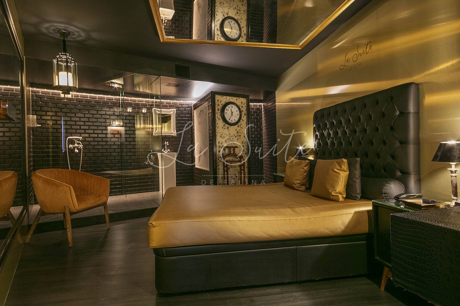 Chambre de luxe, murs noirs et dorés, finitions en bois et mobilier luxueux de couleur dorée à La Suite, Barcelone.