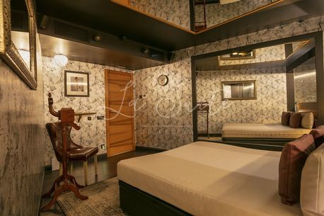 Chambre élégante, murs et sol bleutés avec finitions en bois d'ébène, mobilier marron clair dans La Suite, Barcelone